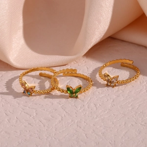 Detailansicht von drei goldenen Schmetterlingsringen mit bunten Edelsteinen und Perlenrand