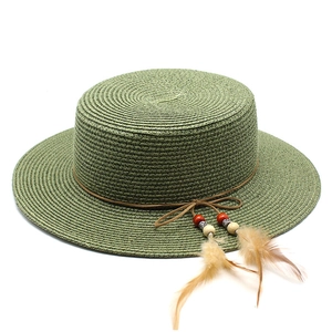 Detail view of light green straw hat with feather pendant and brown cord decoration