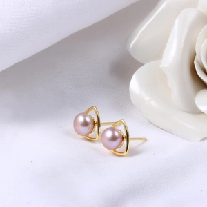 Macro view of triangle stud earrings featuring pink freshwater pearls in gold settings