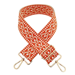 Detail of orange and beige jacquard shoulder strap with gold-tone metal buckles