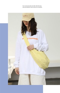 Dettaglio della borsa a tracolla in nylon giallo con felpa bianca in stile casual chic