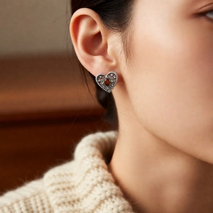 Close-up of vintage silver heart earring with red-brown gemstone and zircon stones