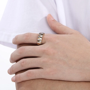 Detail of silver and gold wave pattern textured titanium steel ring on male finger