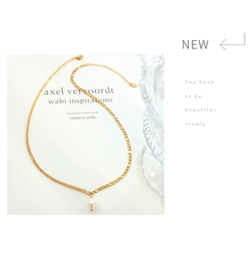 Detail view of double-layer gold chain necklace with freshwater pearl pendant on white books
