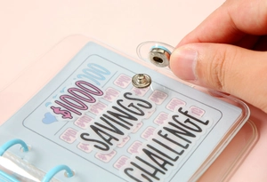 Close-up of clear PVC binder pocket with $1000 savings challenge card and snap closure