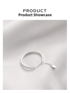Macro shot of 925 silver plated chain ring with oval pendant on white silk fabric