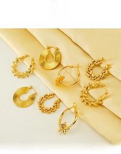 Detail view of four pairs of golden titanium steel earrings on a satin background
