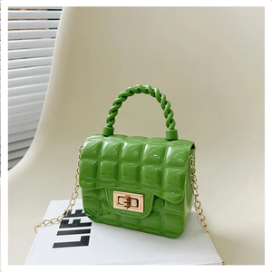 Close-up of green quilted jelly bag with gold chain strap and turn-lock on a gift box