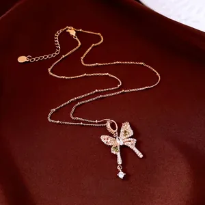 Rose gold butterfly pendant necklace with green gemstones on luxury red silk background