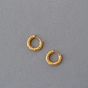 Detailed close-up of gold-plated brass hoop earrings featuring a unique hammered texture