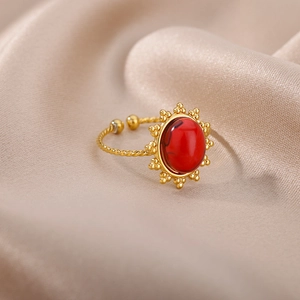 Macro shot of gold bohemian ring with red stone and twisted band on silk fabric