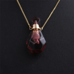 Macro shot of red crystal flame perfume bottle pendant on gold chain with leather background