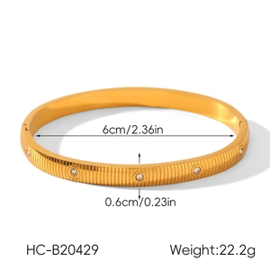 Detail shot of gold striped stainless steel bangle with diamond inlay and size specs