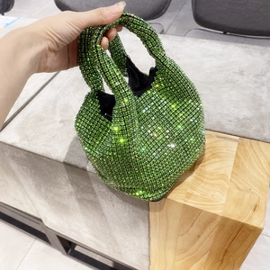 Close-up of emerald green rhinestone bucket bag with crystal handle and black lining
