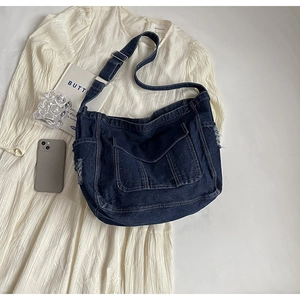 Détail d'un sac cabas en jean bleu vintage avec bords effilochés et poche avant