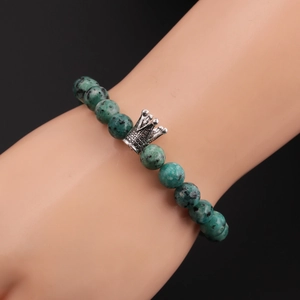 Detailed view of 8mm green natural stone bead bracelet with silver crown on model wrist