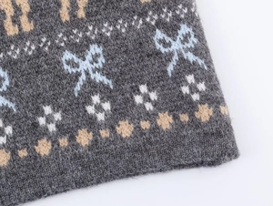 Macro detail of knit fabric featuring blue bow jacquard and star patterns on grey base