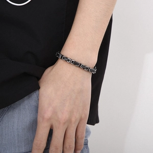 Close-up of a masculine black and silver two-tone stainless steel chain bracelet on a wrist