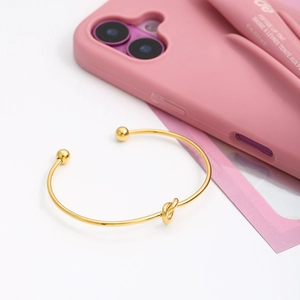 Detail of 18K gold stainless steel knot bangle showing the polished heart design