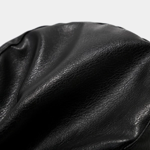 Detailed macro shot of premium black leather texture with natural lychee grain on a military cap