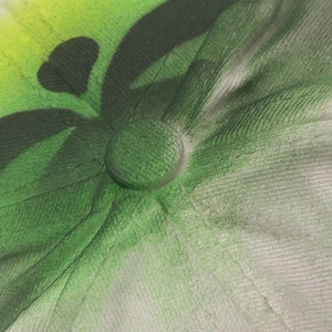 Close-up of baseball cap top button with black floral print on green gradient canvas