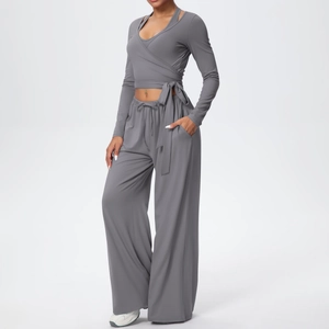Détail d'un ensemble de yoga gris avec haut à nouer et pantalon large de sport