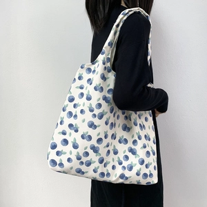 Floral canvas tote bag with blueberry print carried by model against a white wall