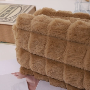 Detail of camel plush pencil case with quilted pattern on a vintage book background