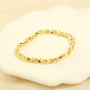 Detail of irregular gold beaded stretch bracelet on a white shell decorative tray