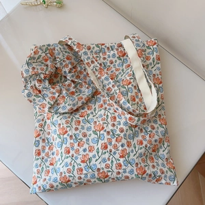 Detailed flat lay of floral cotton tote bag and matching scrunchie on light surface
