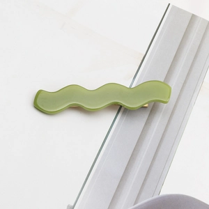 Detailed view of wavy avocado green acetate hair clip with gold metal closure