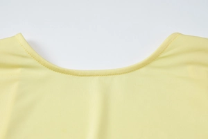 Detailed close-up of the round neckline and fabric texture on a pale yellow dress