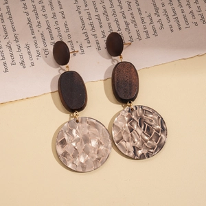 Detailed view of vintage acrylic drop earrings with brown wood and gold textured metal discs