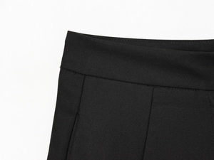 Gros plan sur la taille du pantalon bouffant noir montrant le tissu sergé et la couture