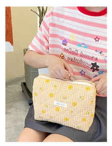 Détail d'une trousse de maquillage jaune matelassée avec sourires et motifs de citrons