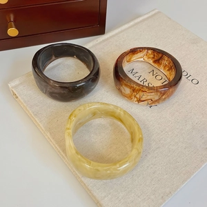 Macro detail of irregular resin bangles with amber texture on linen background