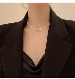 Close-up of a natural pearl choker with a small gold ball on a model's neck
