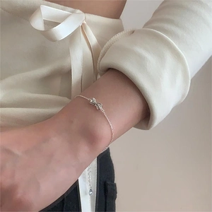 Close-up of a minimalist 925 sterling silver bow bracelet worn on a woman's wrist