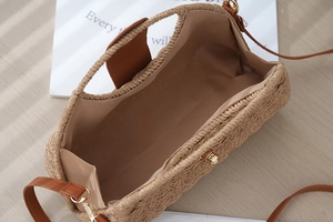 Detail view of woven straw bag opening with magnetic buckle and interior lining