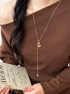 Detail of amber resin heart pendant on golden long chain necklace for women