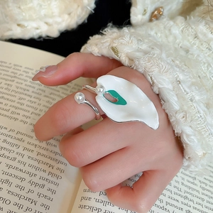Detail of white calla lily ring with green center and small pearls on model hand