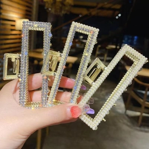 Detailed close-up of golden metal hair claws with rhinestones and faux pearls