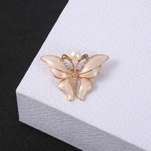 Macro shot of gold butterfly brooch with champagne enamel, white pearl, and colorful rhinestones