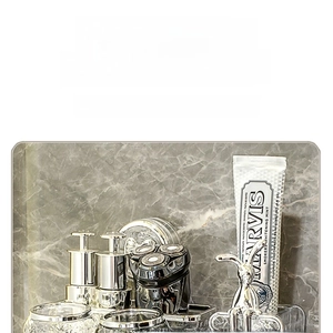 Detail view of transparent glass soap dispenser and mouthwash cup in silver frame set