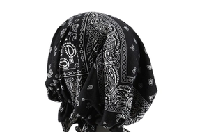 Detail of black pre-tied turban hat featuring classic white paisley pattern and pleats