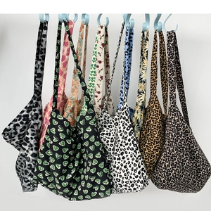 Variety of leopard print and floral canvas tote bags displayed hanging on a white wall