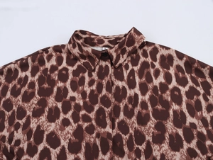 Detail of classic leopard print shirt collar with black button and soft draped fabric