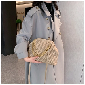 Detail of beige quilted handbag with gold chain strap and elegant fold design