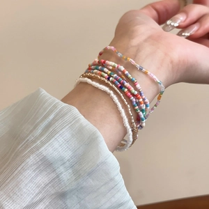 Close-up of bohemian multi-layer rainbow seed bead bracelets worn on a model's wrist