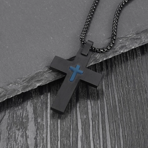 Detailed shot of black stainless steel cross necklace with blue inlay on stone background